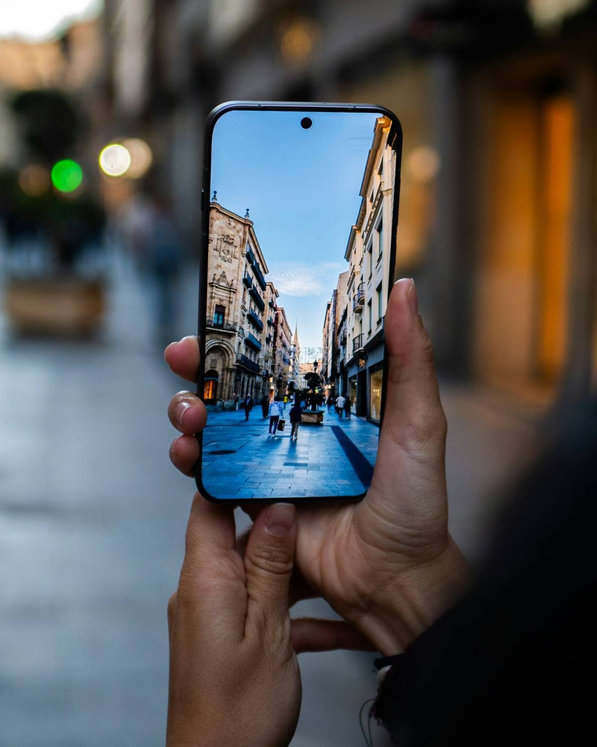 Une main tient un téléphone qui affiche une rue commerçante